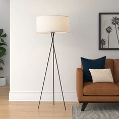 a living room with a chair, lamp and pictures hanging on the wall behind it