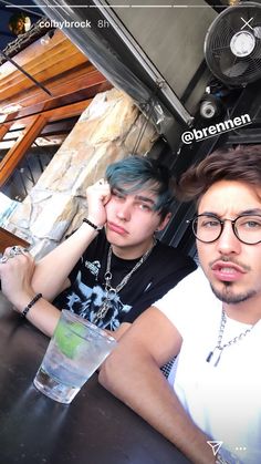 two young men sitting at a table with drinks