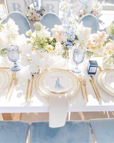 the table is set with blue and white plates, silverware, and floral centerpieces