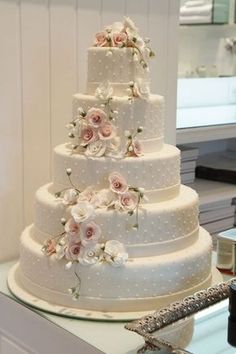 a three tiered wedding cake with pink flowers on the top and white polka dots