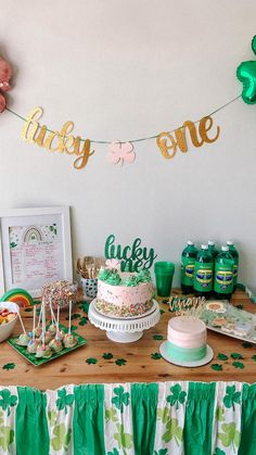 a table topped with cake and candy covered in shamrocks next to a green banner