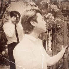 an old photo of a man and woman in front of a tree with two birds on it