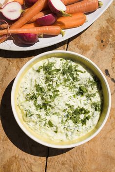 carrots, celery and radishes on a table with dip in a bowl