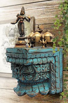 a blue table with two teapots and a statue on top