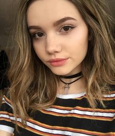 a woman with long hair wearing a black choker and striped shirt is looking at the camera