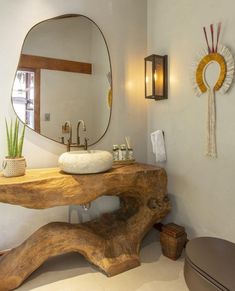 a bathroom with a wooden table and mirror on the wall next to a sink in front of a large round mirror