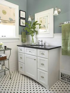 a bathroom with black and white tile flooring and blue walls, along with green towels hanging on the wall