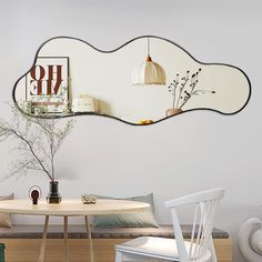 an oval mirror is hanging on the wall above a table with chairs and a vase