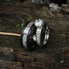 two wedding rings with white and black wood inlays on top of each other