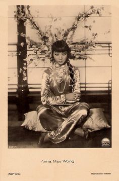 an old photo of a woman sitting on the floor in front of a tree with flowers