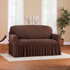 a living room with a couch covered in a brown blanket and a rug on the floor