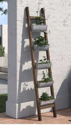 a wooden ladder with plants growing on it in front of a white wall and grass