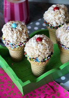 three ice cream cones with sprinkles and candies on a green tray