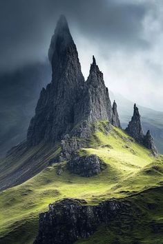 the mountains are covered with green grass and dark clouds in the distance, as if they were foggy