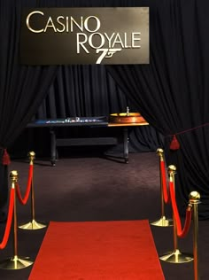 a red carpet and some gold poles on the ground with a casino royale sign in the background