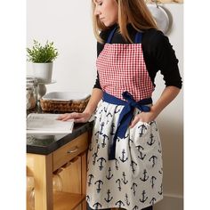 a woman standing in front of a kitchen counter with an apron over her shoulder and looking down