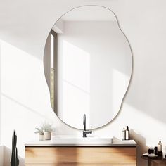 a bathroom with a large round mirror on the wall above the sink and wooden cabinets