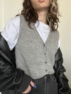 a woman with curly hair wearing a black leather jacket and white shirt is posing for the camera