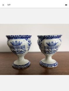 two blue and white vases sitting on top of a wooden table next to each other