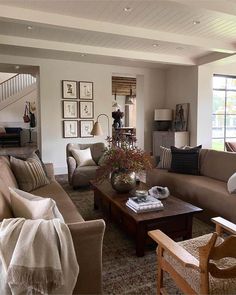 a living room filled with lots of furniture next to a stair case in front of a window