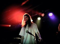 a man with long hair standing in front of a microphone