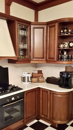 a kitchen with wooden cabinets and white counter tops, black appliances and checkered flooring