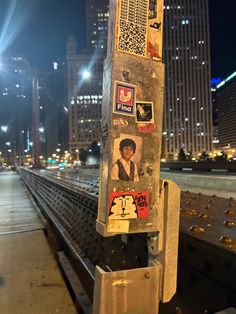 a street sign with stickers on it in the middle of a city at night