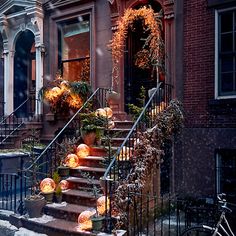 the steps are decorated with pumpkins and plants in front of an apartment building on a snowy day