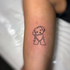 a small black and white dog tattoo on the arm