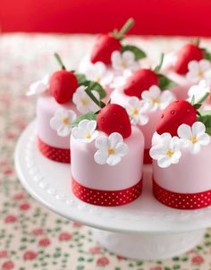 small cakes decorated with strawberries and flowers on a plate