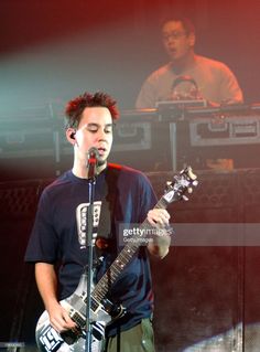 a young man holding a guitar while standing in front of a microphone