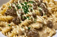 a white plate topped with pasta covered in meat and cheese sauce, garnished with parsley