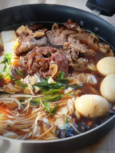 a large pot filled with lots of food on top of a wooden table