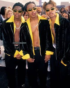 three men in black and yellow jackets standing next to each other at a fashion show