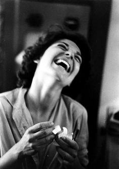 a woman laughing and holding something in her hands