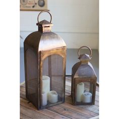 two lanterns sitting on top of a wooden table next to each other with candles in them