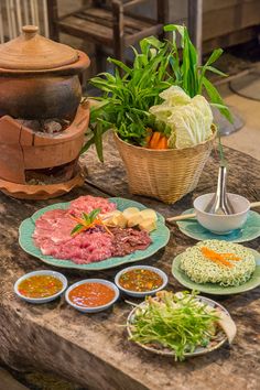 a table topped with plates and bowls filled with different types of food next to a potted plant