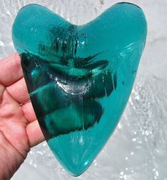 a hand holding a heart shaped glass object