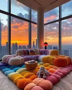 a living room filled with lots of furniture and large windows overlooking the city at sunset