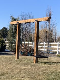 a wooden swing set in the middle of a field