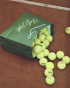 a bag full of tennis balls sitting on the ground next to a line of tennis balls