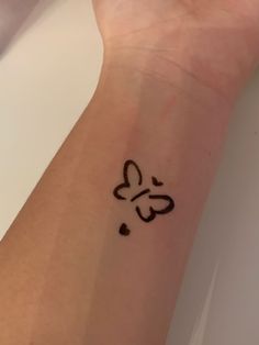 a small tattoo on the wrist of a person with a butterfly and hearts drawn on it