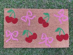 a door mat with cherries and bows on it in the middle of some grass