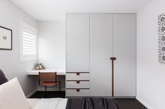 a bedroom with a bed, desk and white cupboards on the wall next to it