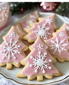 pink and white decorated christmas cookies with snowflakes on them sitting on a plate