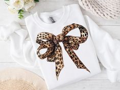 a t - shirt with a leopard print bow on the front, and a straw hat next to it