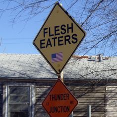 a street sign that says flesh eaters and thunder junction is posted in front of a house