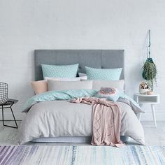 an image of a bedroom with white walls and grey bedding, blue throw pillows