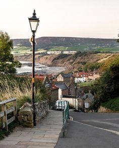 a street light sitting on the side of a road next to a lush green hillside