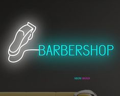 a neon sign that reads barbershop next to a couch